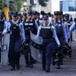 A group of uniformed police officers with shields and protective gear walking together during heightened election security.