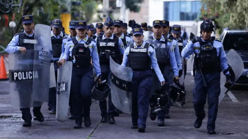 A group of uniformed police officers with shields and protective gear walking together during heightened election security.