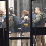 FBI agents and local police gather inside a Brown University building as investigators continue searching for the gunman after a person of interest was released.