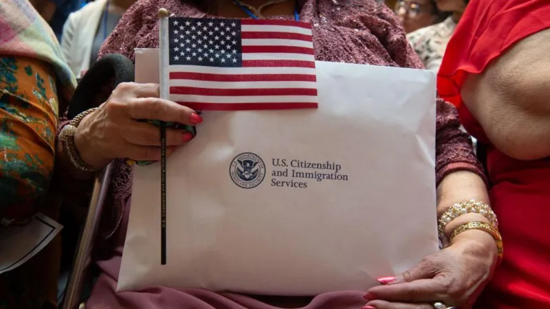 Immigrant holds US flag and USCIS documents as citizenship ceremonies are cancelled under new immigration restrictions
