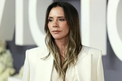 Victoria Beckham wearing a white-and-navy silk midi dress at a NYC holiday event, showcasing her signature quiet-luxury style.