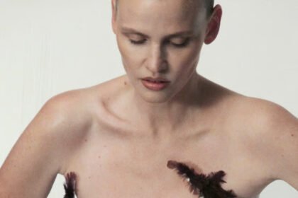 Model wearing a feather-adorned dress from Antony Price’s collection, highlighting bold textures and striking design details