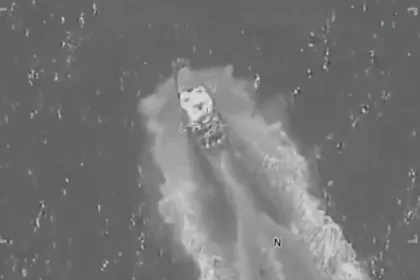 Aerial surveillance image showing a US military strike targeting an alleged drug trafficking boat in the Pacific Ocean, with smoke and wake visible around the vessel.