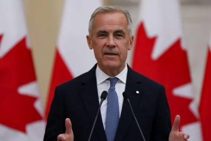 Canada’s prime minister speaks during an official address with Canadian flags in the background amid debate over British versus Canadian spelling