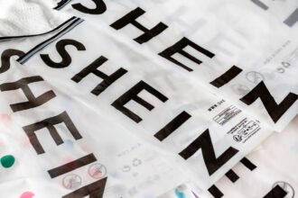 Shein logo on a smartphone screen with Paris skyline in the background