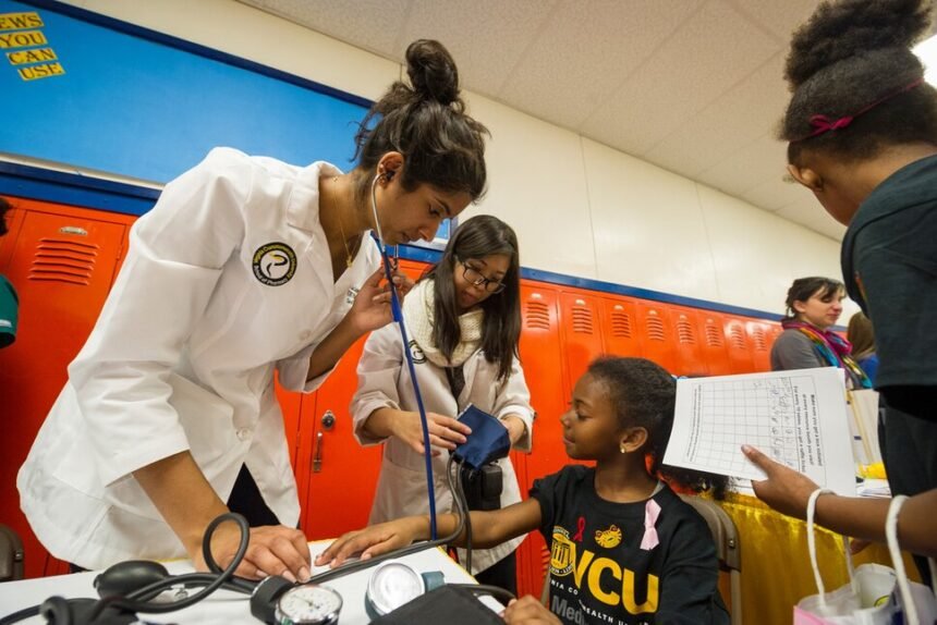 VCU medical students check a young girl’s blood pressure during a community health event, teaching practical healthcare skills.