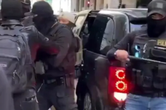 Immigration officers stand near patrol vehicles during an enforcement operation as tensions rise over political criticism