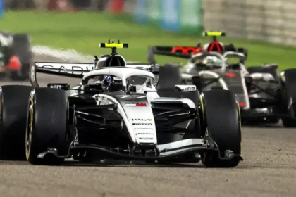 Audi and Cadillac Enter F1: Same Goal, Different Paths Two major car brands are entering Formula 1 in 2026, each with the same ambition but very different approaches. Audi has taken over the Sauber team, while Cadillac, under General Motors, is building a team from scratch. Both see F1’s new hybrid engine rules as a perfect marketing platform for their road-car technologies. Audi: Transforming an Existing Team Audi’s strategy focuses on transforming Sauber into a competitive F1 team. The team has a mix of trackside and factory leadership. Jonathan Wheatley, formerly of Red Bull, manages operations at the track, while Mattia Binotto, ex-Ferrari, runs the technical and factory side. Audi also builds its own engine at Neuburg while improving Sauber’s Hinwil base in Switzerland. Despite early struggles from underinvestment, the team showed progress in 2025, with veteran driver Nico Hulkenberg achieving a podium at the British Grand Prix. Early tests suggest Audi sits in the midfield, competing with Haas, Alpine, and Racing Bulls, while slightly ahead of Williams. The team aims to compete for championships within five years. Cadillac: Building From Scratch Cadillac faced a different challenge. Starting fresh, they had to create an entire team while dealing with F1 politics and delays. Initially, Andretti Global tried to enter the sport, but the bid was rejected. After restructuring and strengthening GM’s role, the entry was approved. Team principal Graeme Lowdon leads the project, supported by technical director Nick Chester. The team operates across multiple locations: Silverstone in the UK, Warren, Michigan, and Charlotte, North Carolina. A new facility in Indiana will serve as the main manufacturing center. Unlike Audi, Cadillac relies on Ferrari customer engines until their own power unit arrives in 2029. The flat management structure and peer-to-peer communication model aim to handle the geographical challenges. Different Challenges, Same Ambition Audi focuses on transforming an existing team and integrating a new engine. Cadillac builds a team and culture from scratch, planning for the long-term with its own power unit. Audi is ready to compete in the midfield immediately, while Cadillac’s real performance will likely start once their engine program is complete. Both have ambitious goals, but they approach F1 from different angles. Key Takeaways Audi transforms Sauber with a strong technical and leadership team. Cadillac builds from zero with a flat, NASA-style management system. Both see F1’s hybrid rules as marketing for their road cars. Audi targets titles within five years; Cadillac has limitless ambitions.