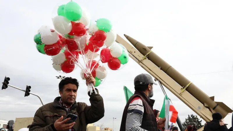 Iran Revolution Anniversary Rallies in Tehran Marked by Loyalty and Growing Discontent Massive Turnout in Tehran for Revolution Anniversary Tehran’s streets filled with large crowds as Iran marked the final day of its Islamic Revolution anniversary celebrations. Supporters of the government gathered in the capital and other major cities in a strong public display of loyalty. Officials treated the rallies as a direct response to recent anti government protests. Families walked together under a warm winter sun. The atmosphere felt festive. Children waved Iranian flags. Many people carried posters of Supreme Leader Ayatollah Ali Khamenei. Chants of “death to America” and “death to Israel” echoed through the streets, a familiar slogan at state organized events. The government’s most loyal supporters showed up in large numbers. Their presence sent a clear political message at a time when public frustration continues to grow over economic hardship. Support for the Revolution Still Runs Deep Many participants expressed strong pride in the 1979 revolution. A young woman wearing a long black veil described the revolution as a turning point for Iran. She said it revived the country and gave new life to society. In her view, its impact extended beyond Iran and influenced the wider Islamic world. Her words reflected a belief shared by many at the rally. For them, the revolution remains a source of identity and national strength. They see it as a symbol of independence and resistance against foreign influence. Acknowledging Economic Frustration At the same time, some supporters admitted that economic problems have caused real frustration. When asked about the recent protests, the young woman said that some people had valid concerns. She acknowledged that many Iranians struggle with rising prices and financial pressure. However, she drew a line between peaceful protest and unrest. She claimed that those who turned protests into chaos acted with motives linked to foreign actors. This argument mirrors the government’s stance. Officials often blame outside forces for fueling instability inside the country. Revolution Celebrations Overshadowed by Tension While the rallies projected unity and strength, they also highlighted divisions within Iranian society. The government aimed to show that it still commands strong public support. Yet the acknowledgment of economic dissatisfaction revealed deeper challenges. Iran continues to face international sanctions, inflation, and political pressure. These issues have sparked repeated protests in recent years. The anniversary events served both as a celebration and as a reminder of the tensions shaping the country today. As Iran reflects on decades since the revolution, the contrast between loyalty and defiance remains clear. Public celebrations showcased pride and commitment. But the undercurrent of economic frustration suggests that the conversation inside Iran is far from settled.