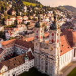 The Abbey Library of St Gallen in eastern Switzerland is a treasure trove of history and knowledge. Its Baroque hall, filled with manuscripts, globes, and unique curiosities, has survived for over 1,300 years, making it one of the world’s oldest and most remarkable libraries. A Journey Back in Time I arrived early in St Gallen when the streets were quiet, and the church bells were still silent. The abbey’s grand stone architecture, with its arched windows, spires, and cloisters, immediately created a sense of awe. Inside, historian Albert Holenstein guided me through echoing corridors to an ornate Baroque doorway. Carved above the entrance was a Greek phrase, "Psyches Iatreion," meaning "healing place of the soul." This ancient inscription hinted at the library’s spiritual and historical significance. A Library of Wonders The library itself is breathtaking. Its intricate wooden bookcases, painted Baroque ceiling, and rows of leather-bound tomes create a scene straight out of a fantasy novel. Terrestrial and celestial globes, Egyptian mummies, and cabinets filled with curiosities from around the world make it feel magical. Items range from silver knives from Turkey to miniature shoes from Indonesia, alongside fossils, shells, and coins. The Abbey Library is more than a collection of religious texts. It houses works on law, music, medicine, astronomy, grammar, arithmetic, rhetoric, and poetry. The abbey served not only as a religious center but also as a hub of education and knowledge, explaining the depth and variety of its collection. Ancient Origins and Rich Heritage The library dates back to the early 7th Century when Irish missionary Saint Gall founded a hermitage that later became the abbey. The current Baroque hall was built in 1767, but the library has preserved its rich heritage. Its collections include 160,000 manuscripts and early printed works, including over 2,100 medieval codices, some written before the year 1000. It also contains the largest collection of Irish manuscripts on mainland Europe, brought by pilgrims traveling to Rome. High German manuscripts in the archive showcase the earliest written examples of the language. Each book tells a story, reflecting the spiritual and intellectual power of written knowledge. Surviving Centuries of Upheaval What makes the Abbey Library of St Gallen truly remarkable is its survival through centuries of political and religious turmoil. Unlike monasteries in England, Wales, and Ireland that were dismantled in the 16th Century, or church properties seized during the French Revolution, St Gallen’s library remained protected. During the abbey’s temporary dissolution between 1797 and 1805, its collections were carefully guarded and preserved by the local Catholic community. Today, the library remains a symbol of learning and history, a place where visitors can experience the wonder of centuries-old manuscripts and treasures.