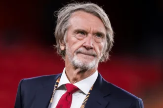 Jim Ratcliffe Immigration Comments Fallout: What It Means for Manchester United The fallout from Jim Ratcliffe’s immigration remarks continues to grow. The Manchester United co owner is now under review by The Football Association, and pressure is mounting from fans, politicians, and commercial partners. His words have triggered serious debate. The consequences could stretch far beyond headlines. FA Reviewing Possible Rule Breach The Football Association is reviewing whether Ratcliffe’s comments brought the game into disrepute. The governing body may charge him, issue a formal warning, or take no action. A charge would escalate the situation quickly. Even a warning would signal that football authorities take the matter seriously. The decision is expected soon. Manchester United Distances Itself Manchester United released a public statement emphasizing its inclusive and welcoming values. The club did not mention Ratcliffe directly. However, the message clearly created distance between the club and his remarks. Senior leadership approved the statement. That shows the level of concern inside Old Trafford. Ratcliffe later apologized. He said he regretted offending people but maintained that immigration policy should be controlled and well managed. Glazer Family and Brand Concerns The Glazer family, who still own 70 percent of the club, have not commented publicly. Sources suggest they were unhappy with the remarks. Manchester United operates as a global brand. Sponsors prefer to associate with positivity and inclusion. Political controversy creates risk, especially when commercial deals are already under pressure. The club currently lacks a training kit sponsor. Its sleeve sponsorship also expires this summer. Meanwhile, the Adidas agreement pays less after two seasons without Champions League football. Although United reported strong commercial revenue last year, competitors continue to close the gap. Stadium Project Could Face Challenges Ratcliffe invested £1.25 billion in 2024 for a 27.7 percent stake in the club. He also backs a proposed 100,000 seat stadium as part of a large Trafford regeneration plan. The project depends on cooperation from political leaders, including Greater Manchester Mayor Andy Burnham and Prime Minister Keir Starmer. Both criticized his comments. Public funding would support infrastructure around the stadium, not the stadium itself. Still, political relationships matter. This controversy arrives at a sensitive moment. One source close to the project said the situation caused real concern, even if it remains manageable. Supporter Reaction and Club Culture Fan groups responded quickly. The Manchester United Supporters Trust said leadership should make inclusion easier, not harder. The Manchester United Muslim Supporters Club called the apology a first step. Members want further reassurance that the club remains welcoming to all communities. Manchester United is one of the most globally diverse clubs in football. Its players, staff, and supporters come from many backgrounds. That makes language around immigration especially sensitive.