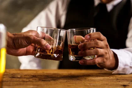 Saudi Arabia has taken a major but quiet step by allowing wealthy foreign residents to legally buy alcohol. This move marks a sharp shift after a nationwide ban that lasted more than seven decades. Observers believe the policy could later include foreign tourists as well. A Discreet Store in Riyadh’s Diplomatic Quarter For many years, Riyadh’s Diplomatic Quarter has felt separate from the rest of the city. The area hosts embassies, luxury housing, green walkways, and cafés popular with young Saudis and expatriates. Inside this exclusive district, an unmarked beige building now serves a new purpose. It houses Saudi Arabia’s first controlled alcohol shop. The store operates quietly and avoids public attention. Officials designed it as a testing ground for easing alcohol restrictions. A Historic Ban Begins to Ease Saudi Arabia banned alcohol sales in 1952. The country is home to Islam’s two holiest sites, which made the ban deeply symbolic. However, the kingdom has changed rapidly in recent years. Under Crown Prince Mohammed bin Salman, the government reopened cinemas and allowed music concerts. Women can now drive. Authorities also limited the power of religious police. The controlled sale of alcohol may be the boldest reform so far. Who Can Buy Alcohol Legally The liquor shop first opened in January 2024. At that time, only non Muslim diplomats could enter. In late 2025, the rules quietly expanded. Now, wealthy non Muslim foreign residents can also shop there. To qualify, an expat must meet one of two conditions. They must hold a Premium Residency permit or earn at least 50,000 Saudi riyals per month. The Premium Residency permit costs 100,000 riyals per year. It usually applies to senior executives, investors, and skilled professionals. Security guards check residence ID cards at the entrance. These cards show both religion and residency status. Expats without the permit must also bring a salary letter from their employer. Tourists remain excluded. Inside the Store Experience Customers say the process feels strict but simple. Staff seal mobile phones in secure bags before entry. Long queues are common and can last over an hour. Inside, shelves carry beer, wine, and spirits. Prices remain high. One British executive said a bottle of whisky cost him 124 dollars. Still, buyers accept the cost because prices remain far lower than black market rates. Several customers spoke anonymously and described the store as well stocked and orderly. What This Change Could Mean This quiet policy shift shows how far Saudi Arabia has moved toward social change. While alcohol remains tightly controlled, the decision signals a softer approach. Many analysts expect gradual expansion, possibly to tourists in the future.