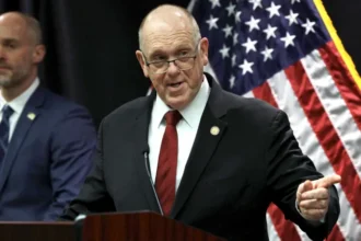 The Trump administration has announced plans to withdraw 700 federal immigration agents from Minnesota. These officers were part of Operation Metro Surge, a major immigration crackdown launched in Minneapolis late last year. White House Border Czar Tom Homan shared the decision during a press conference in Saint Paul on Wednesday. He said the pullback would start immediately. Federal Presence to Be Reduced Gradually According to Homan, agents from Immigration and Customs Enforcement and the US Border Patrol will be included in the withdrawal. Around 2,000 federal agents will remain in Minnesota for now. Homan explained that the administration wants to return to the staffing level that existed before the operation began in December. He said the decision reflects improved cooperation from state and local authorities. He added that federal officials will continue adjusting the number of agents based on local support and coordination. Body Cameras a National Priority During the briefing, Homan said the government is prioritizing body worn cameras for all officers operating in Minnesota. He confirmed that every federal agent in Minneapolis will receive the equipment. The administration also plans to expand body camera use nationwide. Homan said the move aims to improve transparency and accountability during enforcement actions. Operation Called a Success Despite Controversy Homan described Operation Metro Surge as a success, even though it faced legal challenges and public criticism. The operation has sparked nationwide protests and intense debate. Two US citizens, Renee Good and Alex Pretti, died after federal agents shot them during enforcement actions. Their deaths remain a major point of concern for civil rights groups. Homan acknowledged that the operation was not perfect. He said federal agencies improved coordination by creating a clearer chain of command. He noted that the operation now runs more smoothly than before. Arrest Numbers Highlight Enforcement Impact Federal agents have arrested hundreds of individuals since the operation began. Homan said officers detained people accused of serious crimes. These include 14 individuals charged with homicide, 139 charged with assault, 87 registered sex offenders, and 28 alleged gang members. The BBC has not independently confirmed these figures. Homan said the goal of the operation was to remove dangerous individuals from communities. He stressed that public safety remains the administration’s top priority. Cooperation Led to Agent Reduction Homan took direct control of the operation at the end of January. At the time, he said federal staffing would depend on how much support local officials provided. On Wednesday, he said Minnesota authorities showed unprecedented cooperation. That cooperation, he said, led to the decision to cut the federal presence by roughly one third.