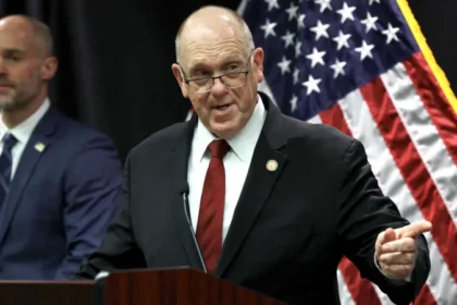 The Trump administration has announced plans to withdraw 700 federal immigration agents from Minnesota. These officers were part of Operation Metro Surge, a major immigration crackdown launched in Minneapolis late last year. White House Border Czar Tom Homan shared the decision during a press conference in Saint Paul on Wednesday. He said the pullback would start immediately. Federal Presence to Be Reduced Gradually According to Homan, agents from Immigration and Customs Enforcement and the US Border Patrol will be included in the withdrawal. Around 2,000 federal agents will remain in Minnesota for now. Homan explained that the administration wants to return to the staffing level that existed before the operation began in December. He said the decision reflects improved cooperation from state and local authorities. He added that federal officials will continue adjusting the number of agents based on local support and coordination. Body Cameras a National Priority During the briefing, Homan said the government is prioritizing body worn cameras for all officers operating in Minnesota. He confirmed that every federal agent in Minneapolis will receive the equipment. The administration also plans to expand body camera use nationwide. Homan said the move aims to improve transparency and accountability during enforcement actions. Operation Called a Success Despite Controversy Homan described Operation Metro Surge as a success, even though it faced legal challenges and public criticism. The operation has sparked nationwide protests and intense debate. Two US citizens, Renee Good and Alex Pretti, died after federal agents shot them during enforcement actions. Their deaths remain a major point of concern for civil rights groups. Homan acknowledged that the operation was not perfect. He said federal agencies improved coordination by creating a clearer chain of command. He noted that the operation now runs more smoothly than before. Arrest Numbers Highlight Enforcement Impact Federal agents have arrested hundreds of individuals since the operation began. Homan said officers detained people accused of serious crimes. These include 14 individuals charged with homicide, 139 charged with assault, 87 registered sex offenders, and 28 alleged gang members. The BBC has not independently confirmed these figures. Homan said the goal of the operation was to remove dangerous individuals from communities. He stressed that public safety remains the administration’s top priority. Cooperation Led to Agent Reduction Homan took direct control of the operation at the end of January. At the time, he said federal staffing would depend on how much support local officials provided. On Wednesday, he said Minnesota authorities showed unprecedented cooperation. That cooperation, he said, led to the decision to cut the federal presence by roughly one third.