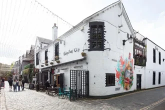 Alasdair Gray Murals on Ubiquitous chip Gain Protected Statute The Ubiquitous chip, one of Glasgow's iconic restaurants, was granted listed building status. This recognition is mainly due to the unique murals painted by the celebrated Scottish artist Alasdair Grey. Historic Environment Scotland officially classifies the building as Category B. The murals in the restaurant are of cultural and artistic importance, as a result. Glasgow Murals that Capture the Creative Spirit Alasdair Grey painted the murals in the early and late 1980s. He was a frequent visitor at the time. In exchange for food and hospitality, he created the art. In the era of that mural, Florid jungle and Arcadia are two rare public works. The vibrant cultural scene in Glasgow's West End is reflected by these works. These works also reflect Gray's strong connection to the local art community. Arcadia shows a group in a garden. This mural features real people from the local community to add a more personal touch. Florid jungle is a colorful and dense natural scene that appears in the courtyard of the restaurant. Cultural Landmarks with Rich History The Ubiquitous chip first opened its doors in 1971. It moved to Ashton Lane, in 1974. The former stables, livery yards and other uses of the building are still evident. It became an important part of Glasgow’s cultural and dining life over time. It was the restaurant that introduced fine Scottish cuisine to the city. The restaurant became a meeting place for writers, artists and performers. Over the years, many well-known people have dined at the restaurant. They include Princess Margaret and Mick Jagger. Greene King purchased the restaurant in 2022 after more than 50-years of family ownership. Gray's Lasting Artistic Legacy Alasdair Grey was born in Glasgow. He became one of Scotland’s most important cultural figures. His work encompassed many different fields including painting, writing and printing. Lanark, his famous novel in Scottish Literature, remains an important landmark. Gray was adamant about bringing art to public places. Gray's work can be found in galleries, pubs, churches and parks all over the city. His work is also on display at the V&A Dundee, and the Scottish National Gallery of Modern Art. Oran Mor is located close to the Ubiquitous Chip. In 2012, a large mural was painted at Hillhead Subway Station. Recognizing the Importance of Public Art Gray, according to experts, wanted to make art available to all. He combines visual art, literature and social concepts in his work. These murals are now protected for future generations. The listing status confirms the importance of these murals in Scotland's culture.