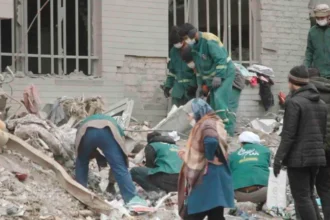 Airstrikes in Tehran trap civilians as they strike residential areas Airstrikes in Tehran have caused a wave of destruction, with families and civilians being buried beneath rubble. Although intended to target military targets, the attacks also affected residential areas. This raises serious questions about civilian safety. Waiting for a Mother Turns into Tragedy A mother in the Resalat neighborhood stood helpless next to the ruin of the apartment her daughter had occupied. She waited for days as rescuers struggled to find those who were trapped under the debris. She repeated that her daughter was alive and well under the rubble, but she was afraid of darkness. The rescue operation was slowed by a lack of manpower. Both the young daughter and mother were later found to be dead. Although the husband was still alive, the death of the daughter and her child devastated the entire family. There is widespread damage in residential zones In seconds, the strike on Resalat destroyed a number of buildings. The Basij is a paramilitary organization associated with the Islamic Revolutionary Guard Corps. Apartment blocks nearby were also destroyed. Satellite and aerial footage shows that four buildings have collapsed. The homes located as far away as 65 meters suffered severe damage. Residents reported hearing multiple explosions in seconds. This suggests that repeated attacks were made within a short period of time. A survivor remembered being thrown around the room. His home, personal items, and documents were all destroyed. After losing their homes, many families are now forced to seek shelter in hotels nearby. The Civilian Death toll is on the Rise According to local sources, this strike killed between 40-50 people. Many of the victims were civilians with no connection to military activities. The attacks were part of a conflict that has been ongoing between Iran, Israel, and the United States. The strikes are aimed at targets linked to the state, but their location in civilian areas increases the danger for non-combatants. The use of powerful bombs raises concerns Analysts believe large bombs, such as the Mark 84 and Mark 80, from the Mark 80 family were used. The weapons have a high impact and explosive power, even if they are guided by precision systems. This assessment is supported by the scale of destruction at Resalat. The entire structure was reduced to rubble and the shockwaves caused damage in surrounding buildings. Civilians caught between conflict and control Now, residents are facing a double-edged sword. One side is the constant airstrikes. They are also under tight internal control after recent crackdowns against protestors. There is a sense of helplessness among many, who have limited or no access to support and safety. The humanitarian costs are increasing as the conflict progresses, particularly in urbanized areas.