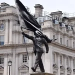 Banksy confirms a new statue in central London at Waterloo Place, showing a suited man with a covered face, placed near historic monuments.