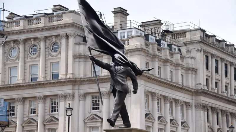 Banksy confirms a new statue in central London at Waterloo Place, showing a suited man with a covered face, placed near historic monuments.