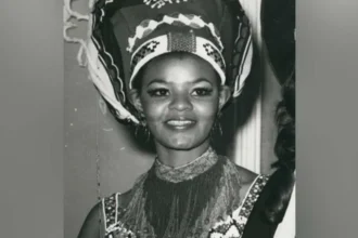 Cynthia Shange, South Africa’s Miss World Pioneer, Dies at Seventy Six Early life and rise to recognition Cynthia Philisiwe Shange was born on twenty seven July nineteen forty nine. She grew up during apartheid in South Africa, a system that restricted opportunities for Black citizens. Despite these barriers, she built a path into public life through beauty pageants and later acting. Breaking barriers in beauty pageants Shange gained national attention after winning Miss Africa South, a contest created because Black women were not allowed to enter Miss South Africa at the time. This achievement opened the door for her to compete internationally. In nineteen seventy two, she represented South Africa at the Miss World competition in London. She stood on the global stage during a period when apartheid shaped every aspect of her country’s identity. She finished in fifth place, making history as the first Black woman to represent South Africa at Miss World. Earlier challenges in the pageant system Before Shange’s participation, Pearl Gladys Jansen also competed internationally as Miss Africa South in nineteen seventy. Her entry caused controversy and highlighted the racial inequalities within global pageants during that era. Acting career and public life After her pageant success, Shange built a long acting career. She appeared in several productions over the years and became known for her strong screen presence. Her work helped expand her influence beyond pageantry into South African entertainment. Death and family tribute Shange passed away in hospital early Monday morning after an illness. She was seventy six years old. Her daughter, Nonhle Thema, confirmed the news and paid tribute to her mother. She described her as a compassionate and graceful woman who brought warmth and kindness to those around her. She also asked for privacy and prayers for the family during this difficult time. Funeral details have not yet been shared. Legacy Cynthia Shange is remembered as a trailblazer who challenged racial barriers during apartheid. Her journey through international pageantry and acting left a lasting mark on South African cultural history.