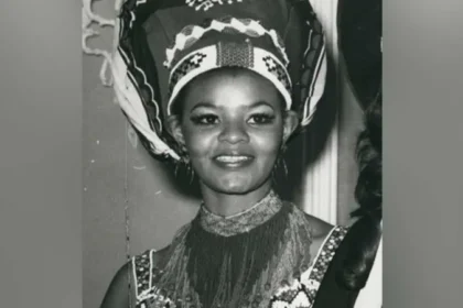Cynthia Shange, South Africa’s Miss World Pioneer, Dies at Seventy Six Early life and rise to recognition Cynthia Philisiwe Shange was born on twenty seven July nineteen forty nine. She grew up during apartheid in South Africa, a system that restricted opportunities for Black citizens. Despite these barriers, she built a path into public life through beauty pageants and later acting. Breaking barriers in beauty pageants Shange gained national attention after winning Miss Africa South, a contest created because Black women were not allowed to enter Miss South Africa at the time. This achievement opened the door for her to compete internationally. In nineteen seventy two, she represented South Africa at the Miss World competition in London. She stood on the global stage during a period when apartheid shaped every aspect of her country’s identity. She finished in fifth place, making history as the first Black woman to represent South Africa at Miss World. Earlier challenges in the pageant system Before Shange’s participation, Pearl Gladys Jansen also competed internationally as Miss Africa South in nineteen seventy. Her entry caused controversy and highlighted the racial inequalities within global pageants during that era. Acting career and public life After her pageant success, Shange built a long acting career. She appeared in several productions over the years and became known for her strong screen presence. Her work helped expand her influence beyond pageantry into South African entertainment. Death and family tribute Shange passed away in hospital early Monday morning after an illness. She was seventy six years old. Her daughter, Nonhle Thema, confirmed the news and paid tribute to her mother. She described her as a compassionate and graceful woman who brought warmth and kindness to those around her. She also asked for privacy and prayers for the family during this difficult time. Funeral details have not yet been shared. Legacy Cynthia Shange is remembered as a trailblazer who challenged racial barriers during apartheid. Her journey through international pageantry and acting left a lasting mark on South African cultural history.