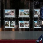 Estate Agents Challenge Rightmove Over Rising Fees Growing Concerns Over Costs Estate agents across the UK are raising concerns about Rightmove’s subscription fees. Many say the costs have increased sharply in recent years, often without a clear rise in services. As property prices stay flat, these rising expenses are putting pressure on agents and their businesses. Legal Action Launched A class action has been initiated against Rightmove. The case, brought forward by accountant Jeremy Newman, represents potentially hundreds of estate agents. The claim seeks nearly £1.5 billion in damages. It alleges that Rightmove has taken advantage of its strong position in the online property market and charged unfair fees. The case has been filed with the Competition Appeal Tribunal, where the claims will be examined in detail. Allegations of Market Dominance The claim argues that Rightmove holds a dominant role in property listings. Because of this position, estate agents feel they have limited alternatives. Many continue using the platform, even though it is costly, because it generates a large share of their leads. Newman, a former Competition and Markets Authority panel member, says agents are being forced to reduce staff. This is because they cannot balance staffing costs with rising subscription fees. As a result, service quality may be affected. Rightmove Responds Rightmove has strongly rejected the allegations. The company says the claim has no merit and that it will defend its position. It also highlights the value it provides to both agents and consumers. According to Rightmove, its platform remains an important tool in the property market. Industry Impact and Reactions Reports from several estate agents show significant fee increases over time. Many say they pay more compared to other platforms. However, they also admit that Rightmove continues to deliver a large number of leads. This creates a difficult situation. Agents feel the platform is essential, but the rising costs are hard to manage. Many believe they have little choice but to stay.