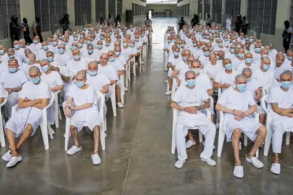 Mass Trial of 486 MS13 Suspects Begins in El Salvador Background of the Case A large scale trial has started in El Salvador involving 486 people accused of belonging to the MS13 gang. Authorities say the suspects are linked to a wide range of serious crimes carried out over a ten year period from 2012 to 2022. Charges and Allegations Prosecutors accuse the group of involvement in more than 47,000 crimes. These include murder, extortion, drug trafficking, arms trafficking, disappearances, and femicide. Officials also say some suspects played roles in violent events in March 2022 when 87 people were killed within a single weekend. Government Response The attorney general’s office says it has strong evidence and expects the court to issue maximum penalties where guilt is proven. The government launched a tough anti gang campaign after the 2022 violence, calling it a war on gangs. Since then, large scale arrests have taken place under a state of emergency that expanded police powers and limited certain constitutional protections. Human Rights Concerns United Nations experts and human rights groups have raised concerns about the trial. They argue that mass proceedings can weaken the right to a fair defense and the presumption of innocence. They also warn that emergency powers have led to possible arbitrary detentions. Despite this, government supporters claim the measures have made the country safer. MS13 Background MS13 is a transnational criminal organization that began in Los Angeles during the 1980s. It was formed by migrants who had fled the Salvadoran civil war. Today, it operates mainly across Central America and has been classified as a terrorist organization by the United States. Legal Process and Current Status Authorities report that 413 suspects are currently in custody, while 73 others are being tried in their absence. The attorney general’s office claims the group has long used violence to control territory and spread fear, affecting both public safety and economic development.