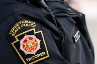 Tragic House Explosion in Clinton County A devastating explosion destroyed a home in Lamar Township, Clinton County, Pennsylvania, on Sunday morning. Authorities confirmed that a 34 year old mother and her six children died in the incident. The children included four boys and two girls, aged between three and eleven. Emergency services arrived at about 08:30 local time after reports of an explosion. They found the house fully on fire and heavily damaged. Fire Spread Before Rescue Could Begin Firefighters reached the scene quickly but faced extreme conditions. The flames spread through the structure at high speed. Officials reported that responders could not safely enter the home to search for survivors. The intensity of the fire caused part of the house to collapse before rescue operations could begin inside the structure. Suspected Cause Under Investigation Investigators believe a propane leak inside the home may have triggered the explosion. However, they have not confirmed the final cause yet. Authorities continue to examine the site and gather evidence. Police stated that the investigation remains active and further findings will be shared once available. Witness Account of the Explosion A nearby resident described hearing a loud blast during breakfast. She said the impact was strong enough to be felt inside her home. She looked outside and saw flames coming from the house. Within a very short time, the entire structure was engulfed in fire. Other neighbors rushed out to call emergency services. Fire crews arrived soon after but reported that the fire had already consumed most of the building. Community Reaction and Ongoing Inquiry The local community expressed shock and grief over the loss of a young family. Neighbors described the fire as fast and overwhelming, leaving almost no time for intervention. Authorities continue to investigate the explosion to determine exactly what caused the propane leak and how the fire spread so quickly.