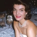 Jackie Kennedy’s 1996 Auction Sparked Public Frenzy The 1996 auction of Jacqueline Kennedy Onassis’s personal belongings turned into one of the most talked-about sales in modern history. Held at Sotheby's in New York, the event drew massive attention from collectors and fans alike. Nearly 1,200 items went up for sale. These included everything from clothing and books to valuable jewelry. What shocked many people was not just the price of items, but the intense public interest. Around 100,000 catalogues were printed, and they quickly sold out. For many buyers, the catalogue itself became a prized keepsake. A Rare Look Into a Private Life Much of the excitement came from curiosity. Jacqueline Kennedy Onassis carefully guarded her personal life. This auction gave people a rare chance to see how she lived behind the scenes. The catalogue featured photos of her home and personal items. These details showed a space that felt warm, elegant, and lived-in. People were not just buying objects. They were connecting with a life that had always seemed distant and refined. A Legacy Linked to History The emotional connection also played a major role. John F. Kennedy’s assassination in Dallas deeply shaped her life and public image. After that tragic moment, she became a symbol of strength and dignity. Many auction items linked back to that period or to the life she rebuilt afterward. This made them more meaningful to buyers. Each piece carried a story tied to a defining chapter in American history. More Than Just an Auction In the end, the auction raised millions of dollars and exceeded all expectations. However, the real story was the public response. People were not simply shopping. They were chasing a connection to a figure who represented grace, style, and mystery. This event showed how powerful a public i
