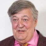 Stephen Fry files injury claim after stage fall at CogX Festival Serious fall after keynote speech British actor and writer Stephen Fry has filed a legal claim after a serious accident at a tech event in London. The incident took place at the CogX Festival, held at the The O2 Arena in September 2023. Fry had just finished his keynote speech on artificial intelligence. He turned to leave the stage but stepped into an unprotected edge. He fell nearly six feet onto a concrete floor behind the stage. Multiple injuries reported The fall caused severe injuries. Fry broke his leg in more than one place. He also suffered fractures in his hip, pelvis, and ribs. Despite the impact, he avoided damage to his spine and head. He later shared that he felt lucky to escape even worse harm. The recovery process took time and careful medical support. Legal action and claims Fry has now filed a personal injury claim in the High Court. He is seeking up to £100,000 in damages. The case targets CogX Festival Ltd and Blonstein Events Ltd. His legal team argues that the stage area was unsafe. They claim the space lacked proper lighting and clear safety barriers. According to the filing, these failures led directly to the fall. Response from organisers CogX representatives have not shared details due to the ongoing case. They confirmed concern for Fry’s condition and wished him a full recovery. Blonstein Events Ltd said it has not received official legal documents yet. The company also stated it does not accept responsibility and is ready to defend its position. What happens next The claim must be formally delivered to the defendants. After that, the court will review both sides. The final decision will determine who is responsible for the incident.