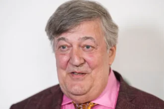 Stephen Fry files injury claim after stage fall at CogX Festival Serious fall after keynote speech British actor and writer Stephen Fry has filed a legal claim after a serious accident at a tech event in London. The incident took place at the CogX Festival, held at the The O2 Arena in September 2023. Fry had just finished his keynote speech on artificial intelligence. He turned to leave the stage but stepped into an unprotected edge. He fell nearly six feet onto a concrete floor behind the stage. Multiple injuries reported The fall caused severe injuries. Fry broke his leg in more than one place. He also suffered fractures in his hip, pelvis, and ribs. Despite the impact, he avoided damage to his spine and head. He later shared that he felt lucky to escape even worse harm. The recovery process took time and careful medical support. Legal action and claims Fry has now filed a personal injury claim in the High Court. He is seeking up to £100,000 in damages. The case targets CogX Festival Ltd and Blonstein Events Ltd. His legal team argues that the stage area was unsafe. They claim the space lacked proper lighting and clear safety barriers. According to the filing, these failures led directly to the fall. Response from organisers CogX representatives have not shared details due to the ongoing case. They confirmed concern for Fry’s condition and wished him a full recovery. Blonstein Events Ltd said it has not received official legal documents yet. The company also stated it does not accept responsibility and is ready to defend its position. What happens next The claim must be formally delivered to the defendants. After that, the court will review both sides. The final decision will determine who is responsible for the incident.