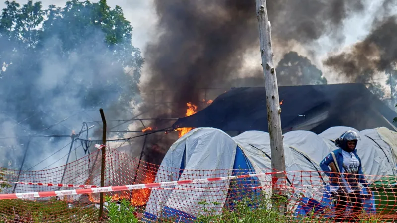 An outbreak of violence erupted at a hospital in eastern Democratic Republic of Congo after the death of a young man suspected of having Ebola. Family members and friends tried to take his body for burial but were stopped by health workers following strict safety rules to prevent infection. The situation quickly escalated. People in the crowd began throwing objects at the facility. Several tents used for isolation and treatment were set on fire. The incident took place at Rwampara General Hospital near Bunia in Ituri province, where most Ebola cases have been recorded. Police responded by firing warning shots to disperse the crowd and regain control of the area. Community reaction and confusion Witnesses said the deceased was a well known local football player. His mother believed he had died from typhoid rather than Ebola, which added to the tension. Local leaders reported that many people in the area do not trust official information about the virus. Some residents believe Ebola is not real or think it is linked to outside organizations and health programs for financial gain. Officials said this lack of trust and awareness is making the response more difficult, especially in remote communities. Medical response and security measures Health workers explained that Ebola burial protocols are essential because the virus remains highly contagious after death. Safe handling of bodies is necessary to prevent further spread. During the unrest, one healthcare worker was injured by stones thrown from the crowd. Medical staff were placed under military protection while security forces restored order at the hospital. Several treatment tents were destroyed in the fire, and at least one body prepared for burial was lost in the chaos. Government response Authorities described the situation as very serious and concerning for public safety. Officials stated that efforts are being increased to improve communication with local communities and to rebuild trust in health services. They emphasized the need for better public awareness so that families understand why strict medical procedures are required during outbreaks.