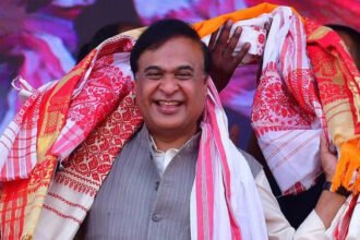 Himanta Biswa Sarma Begins Second Term as Assam Chief Minister Election Victory in Assam Himanta Biswa Sarma has been sworn in again as chief minister of Assam after a strong win for the ruling party. Bharatiya Janata Party won 82 out of 126 seats in the state assembly election. Its partners secured 20 more seats, giving the alliance a clear majority. The party has stayed in power since 2016 and continues to strengthen its position in the region. Political Journey and Rise Sarma represents the Jalukbari constituency near Guwahati, Assam’s largest city. He has held this seat since 2001. He began his political career in the Congress party and worked as a minister under former chief minister Tarun Gogoi. Later, he switched to the Bharatiya Janata Party in 2015. His move brought several supporters with him and weakened the Congress party in Assam. His shift also helped the BJP expand quickly in the region. Role in BJP Expansion in Northeast India Sarma played a major role in building the BJP’s presence across northeast India. The party once had limited support in Assam, with a low vote share for many years. Over time, its support grew significantly and now stands much higher than before. He worked closely with local groups and helped the party form alliances in nearby states. His organizational skills made him an important figure in the party’s regional strategy. Governance and Welfare Programs During his leadership, the state government focused on infrastructure development such as roads and bridges. One of the key welfare schemes is Orunodoi, which provides financial support to women from low income families. Supporters say this program has helped many households across Assam. His administration has also focused on public services and development projects. Criticism and Political Debate Sarma’s leadership has also faced criticism. Opposition parties and rights groups accuse the government of targeting minority communities, especially Bengali speaking Muslims. Issues such as migration, identity, and citizenship remain sensitive in Assam politics. Some policies linked to religious schools and child marriage have sparked public debate. A recent AI generated video shared by the state party unit also triggered controversy before being removed.