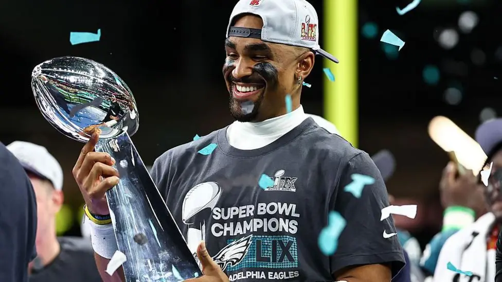 Eagles Set for London Game in 2026 NFL Season as League Expands Globally Philadelphia Eagles Head to London The Philadelphia Eagles will return to London in the 2026 NFL season. They will be part of a major international schedule that includes a record number of games outside the United States. The Eagles last played in London in 2018. The game in London will take place at Tottenham Hotspur Stadium. It adds to the league plan of growing American football across global markets. NFL Expands to Nine International Games The NFL will stage nine regular season games across four continents in 2026. These matches will be played in seven different countries. The United Kingdom will host three games again. The league is also expanding into new regions. Australia and France will host NFL games for the first time. This marks a major step in the sport’s international growth. Jaguars and 49ers Lead Overseas Schedule The Jacksonville Jaguars and San Francisco 49ers will each play two games outside the United States. The Jaguars will also host games in London across two consecutive weeks. The 49ers will take part in international fixtures that include matches in Mexico. The Baltimore Ravens and Dallas Cowboys will also play in Brazil in the league’s first game in Rio de Janeiro. London Games Schedule London will open its NFL run on 4 October. The Washington Commanders will face the Indianapolis Colts at Tottenham Hotspur Stadium. The Jaguars will then host the Eagles the following week at the same venue. After that, they will meet the Houston Texans at Wembley Stadium. This will be a divisional game, which is rare outside the United States. Games Across Europe and Australia The NFL will also stage games in other major cities. Paris will host its first NFL game at Stade de France, where the New Orleans Saints will meet the Pittsburgh Steelers. Real Madrid’s stadium will host a game between the Cincinnati Bengals and Atlanta Falcons. Munich will see the New England Patriots face the Detroit Lions. The opening international game of the season will be played in Australia. The Los Angeles Rams will face the San Francisco 49ers at the Melbourne Cricket Ground. League Reaction and Expansion Goals NFL UK and Ireland leadership said the 2026 schedule features major stadiums and strong matchups. They highlighted the Eagles as a strong and competitive team returning to London. They also noted that divisional games played outside the United States are still uncommon. The Jaguars hosting the Texans in London was described as a key moment for international growth.