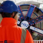 HS2 Project Faces Major Cost Rise and Delay The HS2 rail project in the United Kingdom is now expected to cost up to £102.7bn. The transport secretary confirmed the updated figures and said the government still plans to finish the project despite rising costs and delays. Officials described the situation as a full reset of the programme due to long running issues with spending, planning, and delivery. New Timeline Pushes Completion Further Back Train services on the HS2 line are now expected to begin between 2036 and 2039. This is up to six years later than the earlier target of 2033. The government said the delay is necessary because of ongoing construction challenges and rising costs. Work is still ongoing on key sections of the route between London and Birmingham. Train Speed Reduced to Cut Costs The original design planned for trains to run at 360 km per hour, or 224 miles per hour. That target has now been reduced to 320 km per hour. Officials said the lower speed will help reduce overall costs while still keeping the service significantly faster than existing rail lines. Spending Already Reaches £44.2bn By March 2026, £44.2bn had already been spent on HS2. The revised total cost now sits between £87.7bn and £102.7bn in 2025 prices. When adjusted to 2019 price levels, the total is roughly double the original budget range set under earlier plans. Political Criticism and Defence of the Project The transport secretary said the government inherited a project marked by serious failures in planning and management. She argued that HS2 had shifted from a symbol of progress to a sign of poor delivery. She also defended continuing the project, saying cancelling it would cost nearly as much as completing it, while delivering no transport benefits. She added that major infrastructure projects are still possible, but they require stronger management and better decision making. Project Scope Reduced from Original Plan HS2 was originally planned to extend from London to Manchester and Leeds. Those northern sections were later cancelled under previous governments. The current version of the project focuses on the route between London and Birmingham.