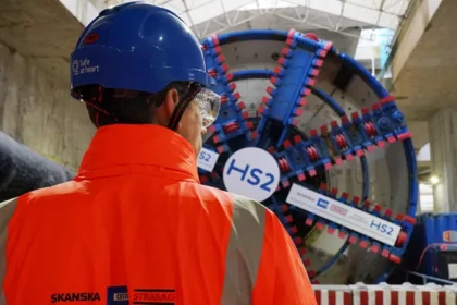 HS2 Project Faces Major Cost Rise and Delay The HS2 rail project in the United Kingdom is now expected to cost up to £102.7bn. The transport secretary confirmed the updated figures and said the government still plans to finish the project despite rising costs and delays. Officials described the situation as a full reset of the programme due to long running issues with spending, planning, and delivery. New Timeline Pushes Completion Further Back Train services on the HS2 line are now expected to begin between 2036 and 2039. This is up to six years later than the earlier target of 2033. The government said the delay is necessary because of ongoing construction challenges and rising costs. Work is still ongoing on key sections of the route between London and Birmingham. Train Speed Reduced to Cut Costs The original design planned for trains to run at 360 km per hour, or 224 miles per hour. That target has now been reduced to 320 km per hour. Officials said the lower speed will help reduce overall costs while still keeping the service significantly faster than existing rail lines. Spending Already Reaches £44.2bn By March 2026, £44.2bn had already been spent on HS2. The revised total cost now sits between £87.7bn and £102.7bn in 2025 prices. When adjusted to 2019 price levels, the total is roughly double the original budget range set under earlier plans. Political Criticism and Defence of the Project The transport secretary said the government inherited a project marked by serious failures in planning and management. She argued that HS2 had shifted from a symbol of progress to a sign of poor delivery. She also defended continuing the project, saying cancelling it would cost nearly as much as completing it, while delivering no transport benefits. She added that major infrastructure projects are still possible, but they require stronger management and better decision making. Project Scope Reduced from Original Plan HS2 was originally planned to extend from London to Manchester and Leeds. Those northern sections were later cancelled under previous governments. The current version of the project focuses on the route between London and Birmingham.