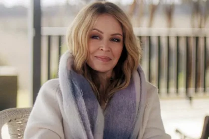 vKylie Minogue shares second cancer diagnosis in 2021 in new documentary Kylie Minogue has revealed that she faced a second cancer diagnosis in 2021, years after her first battle with breast cancer in 2005. She shared the update in her self titled Netflix documentary, where she spoke openly about the emotional weight of the experience and why she chose to keep it private at the time. Second diagnosis kept private Minogue explained that the diagnosis came in early 2021 following a routine medical checkup. Unlike her first cancer battle, she did not share the news publicly. She said she was not able to talk about it while going through treatment and recovery. She described that period as one where she felt emotionally drained and struggled with daily life. Even during major professional success, she was still dealing with the personal impact of illness. Life during recovery and public success While working through recovery, Minogue continued her music career. Her 2023 track Padam Padam became a major global hit and brought renewed attention to her work. She said that even during that success, she knew her health journey was still affecting her deeply. She explained that there were moments when she considered speaking about her diagnosis in interviews but could not bring herself to do it. She said she felt like she was not fully herself at times and preferred to focus on getting better quietly. Reflection on privacy and sharing her story Minogue said she does not feel an obligation to share every personal health detail publicly. However, she decided to include her story in the documentary to help others who may be going through similar experiences. She also highlighted the importance of regular health checkups and early detection. According to her, early diagnosis played a key role in her recovery both times. First cancer diagnosis in 2005 In 2005, Minogue was diagnosed with breast cancer during a routine check. She paused her Showgirl tour and stepped away from major performances to undergo chemotherapy and radiotherapy. The diagnosis was widely reported at the time, and she received strong public support during her treatment and recovery