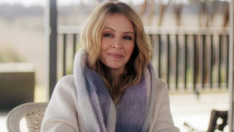 vKylie Minogue shares second cancer diagnosis in 2021 in new documentary Kylie Minogue has revealed that she faced a second cancer diagnosis in 2021, years after her first battle with breast cancer in 2005. She shared the update in her self titled Netflix documentary, where she spoke openly about the emotional weight of the experience and why she chose to keep it private at the time. Second diagnosis kept private Minogue explained that the diagnosis came in early 2021 following a routine medical checkup. Unlike her first cancer battle, she did not share the news publicly. She said she was not able to talk about it while going through treatment and recovery. She described that period as one where she felt emotionally drained and struggled with daily life. Even during major professional success, she was still dealing with the personal impact of illness. Life during recovery and public success While working through recovery, Minogue continued her music career. Her 2023 track Padam Padam became a major global hit and brought renewed attention to her work. She said that even during that success, she knew her health journey was still affecting her deeply. She explained that there were moments when she considered speaking about her diagnosis in interviews but could not bring herself to do it. She said she felt like she was not fully herself at times and preferred to focus on getting better quietly. Reflection on privacy and sharing her story Minogue said she does not feel an obligation to share every personal health detail publicly. However, she decided to include her story in the documentary to help others who may be going through similar experiences. She also highlighted the importance of regular health checkups and early detection. According to her, early diagnosis played a key role in her recovery both times. First cancer diagnosis in 2005 In 2005, Minogue was diagnosed with breast cancer during a routine check. She paused her Showgirl tour and stepped away from major performances to undergo chemotherapy and radiotherapy. The diagnosis was widely reported at the time, and she received strong public support during her treatment and recovery