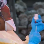 Ebola Outbreak in DR Congo Raises Concern Over Regional Spread Health authorities in the Democratic Republic of the Congo are closely monitoring a growing Ebola outbreak in the eastern part of the country. Early laboratory tests confirmed the virus in several samples collected from suspected patients. The Institut National de Recherche Biomédicale (INRB) in Kinshasa tested 20 samples and detected Ebola in 13 of them. Medical experts are now working to identify the exact strain of the virus. Officials reported 65 deaths linked to the outbreak. However, only four deaths have been confirmed through laboratory testing so far. Health teams continue to investigate other suspected cases in affected areas. Ebola Cases Confirmed in Eastern DR Congo The outbreak has mainly affected parts of Ituri province, including the provincial capital Bunia. Authorities also identified suspected infections in nearby communities. Laboratory teams are still checking samples from those areas. Health workers have increased monitoring efforts to prevent further transmission. Emergency teams are also tracing people who may have come into contact with infected patients. Health Officials Monitor Virus Strain Scientists are conducting more tests to determine the Ebola strain behind the outbreak. Identifying the strain will help medical teams improve response strategies and treatment planning. Health experts continue to study how quickly the virus spreads in the affected regions. Officials believe early detection remains critical for controlling the outbreak. Mining Towns Face Higher Risk Africa CDC warned that mining towns such as Mongwalu face a higher risk of transmission because of crowded conditions and frequent movement of workers. Urban areas like Bunia and Rwampara also remain vulnerable. Large populations and busy transport routes may increase the chances of the virus spreading further. Medical officials urged residents to follow safety guidelines issued by national health authorities. Communities have also received instructions on hygiene practices and reporting symptoms quickly. Regional Coordination Becomes Urgent Africa CDC Executive Director Jean Kaseya said cross border coordination is necessary because many people regularly travel between affected areas and neighboring countries. Health authorities from nearby nations are now discussing emergency response plans and surveillance measures. Officials want to strengthen border monitoring and improve communication between regional health agencies. The Congolese government has not officially declared a national outbreak yet. Authorities are expected to provide more updates as investigations continue and additional test results become available.