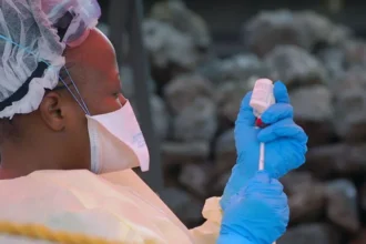 Ebola Outbreak in DR Congo Raises Concern Over Regional Spread Health authorities in the Democratic Republic of the Congo are closely monitoring a growing Ebola outbreak in the eastern part of the country. Early laboratory tests confirmed the virus in several samples collected from suspected patients. The Institut National de Recherche Biomédicale (INRB) in Kinshasa tested 20 samples and detected Ebola in 13 of them. Medical experts are now working to identify the exact strain of the virus. Officials reported 65 deaths linked to the outbreak. However, only four deaths have been confirmed through laboratory testing so far. Health teams continue to investigate other suspected cases in affected areas. Ebola Cases Confirmed in Eastern DR Congo The outbreak has mainly affected parts of Ituri province, including the provincial capital Bunia. Authorities also identified suspected infections in nearby communities. Laboratory teams are still checking samples from those areas. Health workers have increased monitoring efforts to prevent further transmission. Emergency teams are also tracing people who may have come into contact with infected patients. Health Officials Monitor Virus Strain Scientists are conducting more tests to determine the Ebola strain behind the outbreak. Identifying the strain will help medical teams improve response strategies and treatment planning. Health experts continue to study how quickly the virus spreads in the affected regions. Officials believe early detection remains critical for controlling the outbreak. Mining Towns Face Higher Risk Africa CDC warned that mining towns such as Mongwalu face a higher risk of transmission because of crowded conditions and frequent movement of workers. Urban areas like Bunia and Rwampara also remain vulnerable. Large populations and busy transport routes may increase the chances of the virus spreading further. Medical officials urged residents to follow safety guidelines issued by national health authorities. Communities have also received instructions on hygiene practices and reporting symptoms quickly. Regional Coordination Becomes Urgent Africa CDC Executive Director Jean Kaseya said cross border coordination is necessary because many people regularly travel between affected areas and neighboring countries. Health authorities from nearby nations are now discussing emergency response plans and surveillance measures. Officials want to strengthen border monitoring and improve communication between regional health agencies. The Congolese government has not officially declared a national outbreak yet. Authorities are expected to provide more updates as investigations continue and additional test results become available.