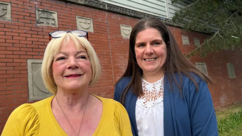 Two neighbours divided by Belfast peace wall turn barriers into friendship Physical wall turns short distance into long walk Lily Brannon, 73, and Michelle Bradley, 46, live in Belfast on opposite sides of a peace wall that separates the Springfield and Springmartin Road areas. Their homes are only about two minutes apart on foot. Because of the wall, the journey between them takes around 20 to 30 minutes. These peace lines exist across parts of Belfast to separate some Catholic nationalist and Protestant unionist communities. Friendship formed through cross community project The two women met through a cross community programme in west Belfast. The initiative runs at the Black Mountain Shared Space building and is supported by the International Fund for Ireland peace barriers programme. At first, both felt cautious. Michelle remembers a sense of reservation. Lily describes it as suspicion. That early tension faded as they spent more time together. From fear to trust Lily grew up before the Troubles, the decades of conflict that ended with the 1998 peace agreement. Michelle was born during the 1980s, when violence was still widespread. Michelle says she did not grow up with hate, but with fear of what she did not know. She believed people on the other side might already dislike her, even without meeting them. Strong bond despite history Over time, the two women built a close friendship. Lily now speaks warmly about Michelle and says she is someone she can rely on. Michelle has also formed a strong bond with Lily. Their relationship shows how everyday contact can reduce long held fears between communities that have been divided for decades. The International Fund for Ireland, which supports this kind of work, is marking 40 years of cross community efforts.