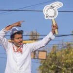Political uncertainty in Tamil Nadu after actor Vijay’s party falls short of majority Historic win but no clear mandate C Joseph Vijay, a well known film star turned politician, has led his newly formed party Tamilaga Vettri Kazhagam (TVK) to a major breakthrough in Tamil Nadu’s state election. The party won 108 seats in the 234 member assembly, becoming the single largest party. However, it still fell 10 seats short of the 118 needed for a majority. This result created a hung assembly, leaving the state without a clear path to form a stable government. Coalition talks begin amid uncertainty After the results, the Indian National Congress, holding five seats, announced its support for TVK. Even so, Vijay still needs at least five more legislators to reach the majority mark. He met Tamil Nadu Governor Rajendra Vishwanath Arlekar and formally staked claim to form the government. The governor later stated that TVK has not yet shown proof of majority support in the assembly. Reports suggest the governor has asked Vijay to demonstrate backing from at least 118 members before any invitation to form government is considered. Debate over constitutional process TVK leaders and allies have criticized the governor’s approach, arguing that the single largest party should normally be given a chance to prove majority on the assembly floor. Legal and constitutional experts remain divided. Some say the governor is acting to ensure political stability, while others believe established convention supports inviting the largest party first and allowing a floor test later. A shift in Tamil Nadu politics TVK’s rise has been compared to earlier political disruptions in the state, especially when MG Ramachandran broke away to form AIADMK and later became chief minister. For decades, Tamil Nadu politics has been dominated by DMK and AIADMK. This election broke that pattern, with TVK emerging as the strongest single party and defeating the ruling DMK. Possible outcomes still open In the past few days, political discussions have intensified. There is even speculation about unlikely alliances between long time rivals. However, analysts say Vijay may still secure support from smaller parties and independents to reach the required number. The final outcome now depends on post election negotiations, not just the vote results.