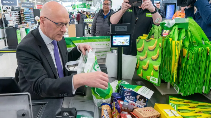 Swinney Defends Food Price Cap Plan Ahead of First Minister Vote SNP Leader Promises Relief for Families Facing Rising Food Costs John Swinney has defended his proposal to cap the prices of essential food items as he prepares for a key vote to remain Scotland’s first minister. He said the policy focuses on helping families manage the ongoing cost of living crisis rather than creating political conflict with the UK government. Speaking ahead of the parliamentary vote, Swinney explained that many households continue to struggle with the rising cost of groceries. According to him, the government has a responsibility to make healthy and basic food items more affordable for the public. Under the proposed SNP plan, major supermarkets in Scotland would have to limit the prices of up to 50 everyday products. These products could include milk, eggs, rice, cheese, and other household essentials. The policy aims to reduce pressure on low and middle income families who are finding it difficult to keep up with food expenses. Supermarkets and Retailers Raise Concerns The proposal has already sparked debate among retailers and business groups. The Scottish Retail Consortium criticized the plan and called it unrealistic. Retail representatives warned that smaller stores could struggle to compete because the price cap would mainly target large supermarket chains. Business leaders also argued that limiting prices could create challenges for suppliers and retailers. However, Swinney responded by saying the government would work closely with supermarkets, producers, and other stakeholders before finalizing the legislation. He stressed that public support remains his main concern because many people across Scotland continue to face financial hardship. Swinney added that discussions with retailers would play an important role in making the policy practical and effective. UK Law Could Create Challenges The SNP leader admitted that introducing the food pricing law may require cooperation with the UK government. Experts believe the proposal could conflict with the UK Internal Market Act 2020, which was introduced after Brexit to prevent trade barriers between Scotland, England, Wales, and Northern Ireland. Since the SNP no longer holds a parliamentary majority, Swinney acknowledged that he would need support from opposition parties in Holyrood as well as discussions with ministers in Westminster. Despite criticism from political opponents, Swinney rejected claims that the policy was designed to trigger a political dispute with London. Instead, he insisted that his goal is to support people who are struggling to afford basic shopping needs. Additional Promises in SNP Manifesto Alongside the food pricing proposal, the SNP has also promised to introduce a £2 cap on bus fares and expand childcare services across Scotland. The party says these measures would help reduce financial pressure on working families and improve access to affordable public services. Swinney believes the combined policies would provide direct support to households dealing with inflation and rising living costs.