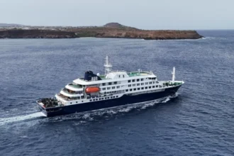 Third British National Suspected of Hantavirus on MV Hondius Cruise as Cases Rise Outbreak Overview on MV Hondius Health officials are monitoring a hantavirus outbreak linked to the cruise ship MV Hondius. A third British national is now suspected to have the infection. The case involves a passenger currently on the remote Atlantic island of Tristan da Cunha after the ship made a stop there in mid April. Two other British men already have confirmed infections. One patient remains in a stable condition in the Netherlands after evacuation from the ship. The second patient is in intensive care in South Africa following an earlier medical transfer. One passenger has died, and the total number of confirmed cases has reached five. Confirmed and Suspected Cases Authorities confirmed that the suspected third British case is under observation and has not yet been fully diagnosed. Two additional British nationals are self isolating at home in the United Kingdom. They show no symptoms and are isolating voluntarily after possible exposure. A group of 30 passengers from around a dozen countries disembarked earlier at St Helena on 24 April. Seven of them were British citizens. Four British passengers who left the ship remain on St Helena and continue to show no symptoms while staying in contact with health teams. Evacuation and Medical Response Medical teams evacuated three patients from the ship earlier in the week. Martin Anstee, a 56 year old retired police officer and expedition guide, was flown to the Netherlands along with a 41 year old Dutch crew member and a 65 year old German passenger. He is currently in stable condition and reports that he feels well. Health authorities plan to send medical support to remote island locations where exposed passengers are being monitored. Teams are focusing on early detection and containment to prevent further spread. Passenger Monitoring and Isolation Measures Passengers who remain on board the MV Hondius will be flown back to the United Kingdom via a chartered aircraft once the ship reaches the Canary Islands. Officials confirmed that all returning passengers will need to isolate after arrival, even if they show no symptoms. Health monitoring continues for all exposed individuals across multiple locations, including Europe, Africa, and remote Atlantic islands. Operator Response and Contact Tracing The cruise operator Oceanwide Expeditions stated that the first confirmed infection was reported on 4 May. The company also confirmed that all passengers who had disembarked were contacted and informed about potential exposure risks.