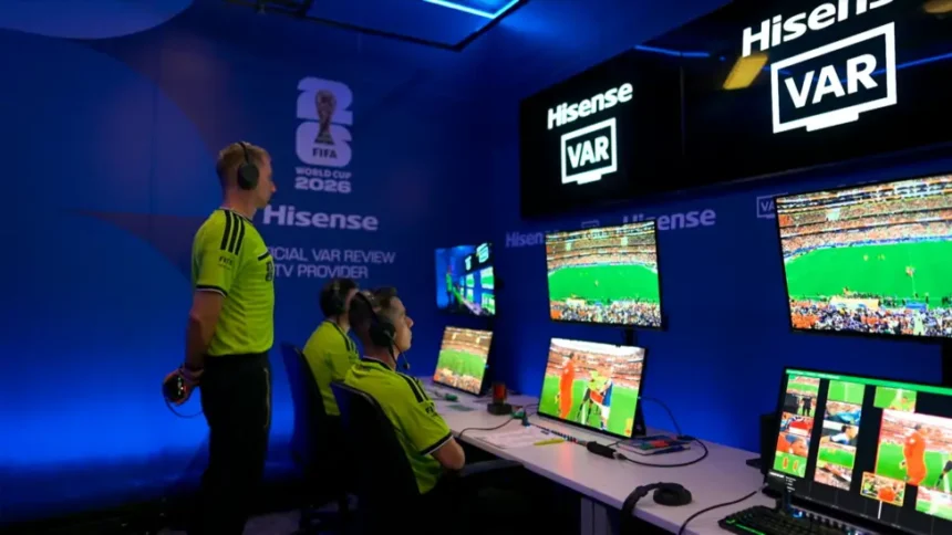# FIFA Investigates VAR Official's Hand Gesture Before Germany's World Cup Match FIFA has launched an inquiry after video assistant referee Shaun Evans made a hand gesture during the pre-match broadcast of Germany's World Cup clash against Curacao. The incident occurred moments before Germany secured a dominant 7 to 1 victory on Sunday. During the official World Cup broadcast, cameras briefly introduced the refereeing team and the VAR officials working from the referee operations hub in Dallas. While the camera focused on the VAR room, Evans appeared to make an upside-down "OK" hand sign. Viewers quickly noticed the gesture, and discussions spread across social media platforms. Many users questioned its meaning and whether it carried any controversial message. ## FIFA Requests Clarification Sources indicate that FIFA is seeking an explanation from the Australian official regarding the gesture. The governing body has not yet released a formal public statement. The incident attracted widespread attention because the hand sign can have different interpretations. Some viewers believed it was harmless, while others linked it to more concerning symbolism. Following the controversy, broadcasts of later World Cup matches appeared to change their presentation style. Instead of facing the camera, VAR officials remained focused on their monitors during pre-match introductions. ## What Does the Upside-Down OK Sign Mean? The upside-down "OK" sign has several possible meanings. One common interpretation comes from the popular "circle game." In this prank, a person forms the symbol below their waist. If someone looks directly at it, they lose the game and may receive a playful punch on the shoulder. The gesture gained popularity through internet culture and television shows before becoming a widely recognized online meme. However, the symbol has also been associated with far-right groups in recent years. Anti-discrimination organizations have noted that some extremists adopted the sign as a way to communicate with supporters or attract attention online. Because of these associations, the gesture has become controversial in certain contexts. ## Anti-Discrimination Groups Seek Answers Several organizations that monitor discrimination and racism in football have requested further clarification about the incident. Experts from anti-discrimination groups stated that the gesture closely resembles a symbol that has been used within some far-right circles. As a result, they believe the matter deserves careful review. The incident has renewed discussions about the importance of maintaining inclusive standards at major international sporting events. ## Experienced Official Under Scrutiny Shaun Evans is one of Australia's most experienced football officials. He has served on FIFA's international referees list since 2017 and has worked at major tournaments, including the 2022 FIFA World Cup. He has also officiated in Australia's top professional league for many years and previously handled a national championship final. As FIFA continues its review, football fans and anti-discrimination groups await further clarification regarding the meaning and intent behind the gesture.