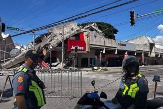 # Major Earthquake in Southern Philippines Kills 32, Triggers Tsunami Alerts A powerful 7.8 magnitude earthquake struck off the coast of Mindanao in the southern Philippines on Monday morning, leaving at least 32 people dead and more than 100 injured. The strong tremor caused widespread destruction, triggered tsunami warnings across several countries, and forced thousands of residents to evacuate. Authorities continue to assess the full impact of the disaster as rescue teams search for missing people and clear damaged areas. ## Tsunami Warnings Issued Across the Region The earthquake occurred at 7:37 AM local time near Mindanao, the Philippines' second largest island. Shortly after the quake, officials issued tsunami alerts for the Philippines, Indonesia, Japan, and Australia. Emergency agencies closely monitored coastal areas. Although authorities later cancelled some warnings, many residents moved to safer locations as a precaution. ## Death Toll Rises as Rescue Efforts Continue Local officials reported that at least 32 people lost their lives due to the earthquake and its aftermath. Many deaths occurred when landslides struck communities in the province of Sarangani, located close to the quake's epicentre. Rescue workers continue searching for nearly two dozen missing individuals. More than 100 people suffered injuries, while emergency teams remain on high alert. ## Sarangani and General Santos Among Worst-Hit Areas Sarangani province recorded the highest number of fatalities, with 17 confirmed deaths. Landslides caused much of the destruction in the area. The earthquake also temporarily disrupted power and communication services, though crews restored most connections later in the day. General Santos City, the closest major city to the epicentre, reported 10 deaths. Authorities also confirmed that several residents remain unaccounted for. The city is widely known for its fishing industry and as the hometown of former world boxing champion and politician Manny Pacquiao. ## Buildings Collapse and Infrastructure Suffers Damage The powerful quake damaged homes, roads, and commercial buildings across several provinces. Videos shared online showed significant structural damage, including the collapse of a Jollibee fast-food restaurant. Authorities also reported damage in South Cotabato and Sultan Kudarat. Engineers are inspecting buildings to determine whether they remain safe for public use. ## Thousands Evacuated for Safety Officials evacuated approximately 10,000 residents from vulnerable areas after the earthquake. Emergency shelters opened to accommodate affected families. Schools in several regions suspended classes following the disaster. The earthquake struck on the first day of the new school year, disrupting activities for thousands of students. In Davao Occidental, footage from a local school showed students gathering in open spaces while the ground shook. Despite the frightening scenes, school officials confirmed that no students suffered injuries. ## Government Mobilizes Disaster Response Philippine President Ferdinand Marcos Jr directed government agencies to coordinate relief and rescue operations. Authorities continue delivering assistance to affected communities and monitoring conditions in high-risk areas. Emergency teams are expected to provide updated casualty figures and damage assessments as rescue operations progress. ## Ongoing Assessment Mindanao is home to approximately 26 million people, making it one of the country's most populated regions. Officials warn that casualty numbers may change as verification efforts continue. Authorities are urging residents to remain cautious, follow safety instructions, and stay informed through official channels while recovery efforts move forward.