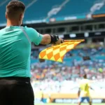 FIFA Introduces New Semi Automated Offside Technology for 2026 World Cup Faster Offside Decisions with Real Time Alerts FIFA will roll out an upgraded semi automated offside system at the 2026 World Cup. The aim is to speed up VAR decisions and reduce long stoppages during matches. Assistant referees will now receive instant audio alerts when a player is more than 10cm offside. This update means the assistant does not always need to wait for play to fully continue before reacting. However, the assistant referee still controls when to raise the flag and stop the game. How the New System Works The new technology builds on earlier versions tested at major tournaments such as the Club World Cup and the Intercontinental Cup. Earlier systems only triggered alerts when a player was clearly offside by more than 50cm. The updated version increases precision and reacts to tighter margins. FIFA has also added safeguards. If there is any suspicion of a technical fault, officials can ignore the alert and rely on standard judgment. Limits of the Technology The system does not solve every offside situation. It still struggles with very tight calls where players are almost level. It also becomes less reliable when players are on the ground or when multiple players are close together. It is designed only for positional offside decisions. It cannot decide subjective cases, such as whether a player interfered with an opponent without touching the ball. AI Player Scanning and 3D Models FIFA will also use AI powered 3D avatars of every player at the tournament. All 1,248 players across the 48 teams will be digitally scanned during pre tournament sessions. Each scan takes about a second and is done once during official photo shoots. These digital models will help produce clearer and more accurate offside graphics for TV broadcasts. Safety Concerns Behind the Change The move also responds to concerns about delayed flags and player safety. In one serious incident in 2025, Nottingham Forest striker Taiwo Awoniyi suffered a severe injury after a delayed offside decision led to continued play. FIFA hopes faster alerts will reduce these risks and prevent unnecessary collisions during live play. What Fans Can Expect At the 2026 World Cup, fans should see quicker decisions, fewer long VAR pauses, and clearer offside visuals on screen. The goal is a smoother viewing experience with fewer controversial delays.
