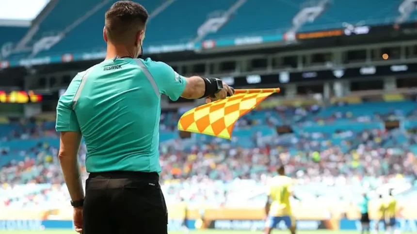 FIFA Introduces New Semi Automated Offside Technology for 2026 World Cup Faster Offside Decisions with Real Time Alerts FIFA will roll out an upgraded semi automated offside system at the 2026 World Cup. The aim is to speed up VAR decisions and reduce long stoppages during matches. Assistant referees will now receive instant audio alerts when a player is more than 10cm offside. This update means the assistant does not always need to wait for play to fully continue before reacting. However, the assistant referee still controls when to raise the flag and stop the game. How the New System Works The new technology builds on earlier versions tested at major tournaments such as the Club World Cup and the Intercontinental Cup. Earlier systems only triggered alerts when a player was clearly offside by more than 50cm. The updated version increases precision and reacts to tighter margins. FIFA has also added safeguards. If there is any suspicion of a technical fault, officials can ignore the alert and rely on standard judgment. Limits of the Technology The system does not solve every offside situation. It still struggles with very tight calls where players are almost level. It also becomes less reliable when players are on the ground or when multiple players are close together. It is designed only for positional offside decisions. It cannot decide subjective cases, such as whether a player interfered with an opponent without touching the ball. AI Player Scanning and 3D Models FIFA will also use AI powered 3D avatars of every player at the tournament. All 1,248 players across the 48 teams will be digitally scanned during pre tournament sessions. Each scan takes about a second and is done once during official photo shoots. These digital models will help produce clearer and more accurate offside graphics for TV broadcasts. Safety Concerns Behind the Change The move also responds to concerns about delayed flags and player safety. In one serious incident in 2025, Nottingham Forest striker Taiwo Awoniyi suffered a severe injury after a delayed offside decision led to continued play. FIFA hopes faster alerts will reduce these risks and prevent unnecessary collisions during live play. What Fans Can Expect At the 2026 World Cup, fans should see quicker decisions, fewer long VAR pauses, and clearer offside visuals on screen. The goal is a smoother viewing experience with fewer controversial delays.