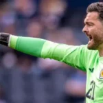 Scotland World Cup Squad: Gordon Set to Be Oldest Player as Gunn Gets No 1 Shirt Scotland’s World Cup squad numbers have been confirmed, with veteran goalkeeper Craig Gordon set to make history as the oldest player at the tournament. Despite this milestone, the 43 year old has not been given the No 1 shirt. Angus Gunn has been assigned the No 1 jersey and is expected to be the first choice goalkeeper. Liam Kelly will wear No 12, while Gordon takes No 21 in the final squad list submitted by the national team. Manchester United teenager Tyler Fletcher has been handed No 8 after replacing injured midfielder Billy Gilmour in the squad at short notice. His inclusion is one of the notable changes in Steve Clarke’s final selection. Scotland’s attacking options have also been clearly numbered. Lyndon Dykes will wear No 9, Che Adams takes No 10, and Lawrence Shankland has been given No 20. These selections may give some hints about the manager’s preferred forward setup, although the starting line up is still not confirmed. In defence and midfield, Grant Hanley has been given No 5, while other key squad members include Andy Robertson, Scott McTominay, and John McGinn. Scotland will continue their preparations with a final warm up match against Bolivia before heading into the tournament. Their opening World Cup group game will follow against Haiti in Boston, before facing Morocco and Brazil. Scotland Squad Numbers Overview Goalkeepers Angus Gunn (1), Liam Kelly (12), Craig Gordon (21) Defenders Aaron Hickey, Andy Robertson, Grant Hanley, Kieran Tierney, Jack Hendry, Dominic Hyam, Anthony Ralston, Nathan Patterson, Scott McKenna, John Souttar Midfielders Scott McTominay, John McGinn, Tyler Fletcher, Ryan Christie, Lewis Ferguson, Kenny McLean, Findlay Curtis Forwards Lyndon Dykes, Che Adams, Lawrence Shankland, Ross Stewart, George Hirst, Ben Gannon Doak