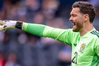 Scotland World Cup Squad: Gordon Set to Be Oldest Player as Gunn Gets No 1 Shirt Scotland’s World Cup squad numbers have been confirmed, with veteran goalkeeper Craig Gordon set to make history as the oldest player at the tournament. Despite this milestone, the 43 year old has not been given the No 1 shirt. Angus Gunn has been assigned the No 1 jersey and is expected to be the first choice goalkeeper. Liam Kelly will wear No 12, while Gordon takes No 21 in the final squad list submitted by the national team. Manchester United teenager Tyler Fletcher has been handed No 8 after replacing injured midfielder Billy Gilmour in the squad at short notice. His inclusion is one of the notable changes in Steve Clarke’s final selection. Scotland’s attacking options have also been clearly numbered. Lyndon Dykes will wear No 9, Che Adams takes No 10, and Lawrence Shankland has been given No 20. These selections may give some hints about the manager’s preferred forward setup, although the starting line up is still not confirmed. In defence and midfield, Grant Hanley has been given No 5, while other key squad members include Andy Robertson, Scott McTominay, and John McGinn. Scotland will continue their preparations with a final warm up match against Bolivia before heading into the tournament. Their opening World Cup group game will follow against Haiti in Boston, before facing Morocco and Brazil. Scotland Squad Numbers Overview Goalkeepers Angus Gunn (1), Liam Kelly (12), Craig Gordon (21) Defenders Aaron Hickey, Andy Robertson, Grant Hanley, Kieran Tierney, Jack Hendry, Dominic Hyam, Anthony Ralston, Nathan Patterson, Scott McKenna, John Souttar Midfielders Scott McTominay, John McGinn, Tyler Fletcher, Ryan Christie, Lewis Ferguson, Kenny McLean, Findlay Curtis Forwards Lyndon Dykes, Che Adams, Lawrence Shankland, Ross Stewart, George Hirst, Ben Gannon Doak