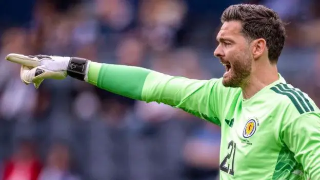 Scotland World Cup Squad: Gordon Set to Be Oldest Player as Gunn Gets No 1 Shirt Scotland’s World Cup squad numbers have been confirmed, with veteran goalkeeper Craig Gordon set to make history as the oldest player at the tournament. Despite this milestone, the 43 year old has not been given the No 1 shirt. Angus Gunn has been assigned the No 1 jersey and is expected to be the first choice goalkeeper. Liam Kelly will wear No 12, while Gordon takes No 21 in the final squad list submitted by the national team. Manchester United teenager Tyler Fletcher has been handed No 8 after replacing injured midfielder Billy Gilmour in the squad at short notice. His inclusion is one of the notable changes in Steve Clarke’s final selection. Scotland’s attacking options have also been clearly numbered. Lyndon Dykes will wear No 9, Che Adams takes No 10, and Lawrence Shankland has been given No 20. These selections may give some hints about the manager’s preferred forward setup, although the starting line up is still not confirmed. In defence and midfield, Grant Hanley has been given No 5, while other key squad members include Andy Robertson, Scott McTominay, and John McGinn. Scotland will continue their preparations with a final warm up match against Bolivia before heading into the tournament. Their opening World Cup group game will follow against Haiti in Boston, before facing Morocco and Brazil. Scotland Squad Numbers Overview Goalkeepers Angus Gunn (1), Liam Kelly (12), Craig Gordon (21) Defenders Aaron Hickey, Andy Robertson, Grant Hanley, Kieran Tierney, Jack Hendry, Dominic Hyam, Anthony Ralston, Nathan Patterson, Scott McKenna, John Souttar Midfielders Scott McTominay, John McGinn, Tyler Fletcher, Ryan Christie, Lewis Ferguson, Kenny McLean, Findlay Curtis Forwards Lyndon Dykes, Che Adams, Lawrence Shankland, Ross Stewart, George Hirst, Ben Gannon Doak